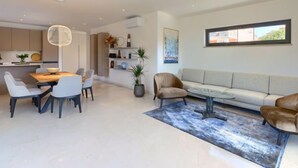 Un salon moderne comprenant un canapé, une table à manger avec des chaises, une table basse et une grande fenêtre.