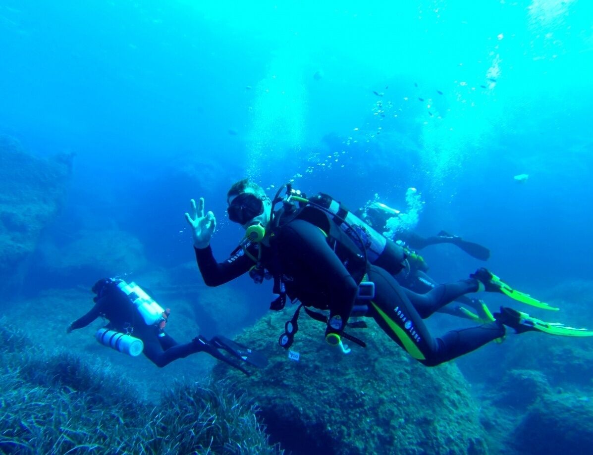 Three scuba divers underwater with their equipment.
