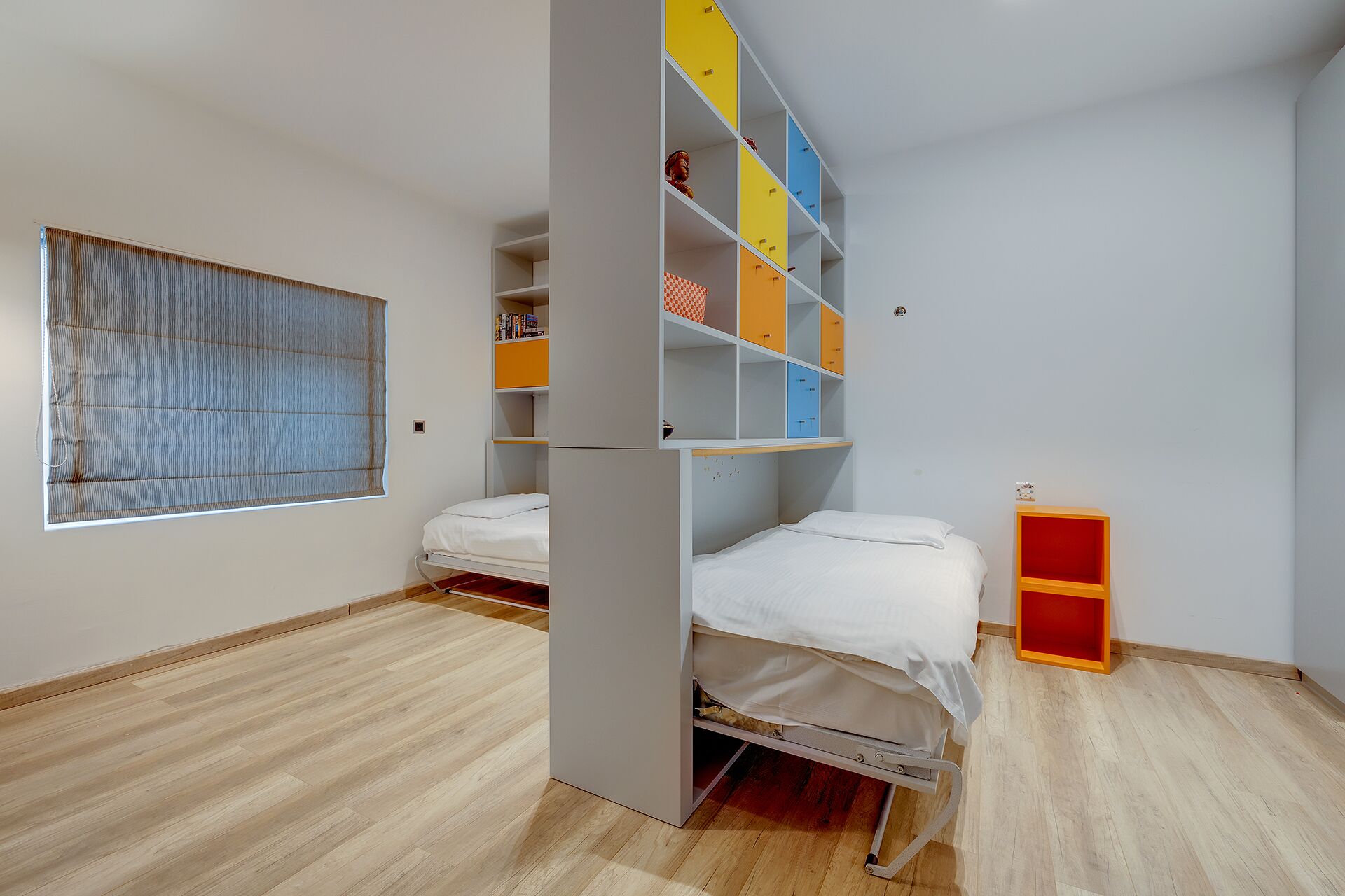 Ein Zimmer mit einem Etagenbett, einem kleinen Schreibtisch und einem Fenster mit Jalousien.