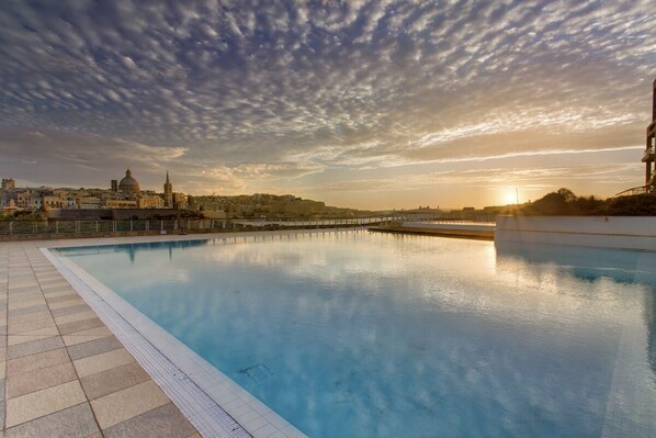 A swimming pool with a clear view of a cityscape in the background, including a prominent dome and spire.