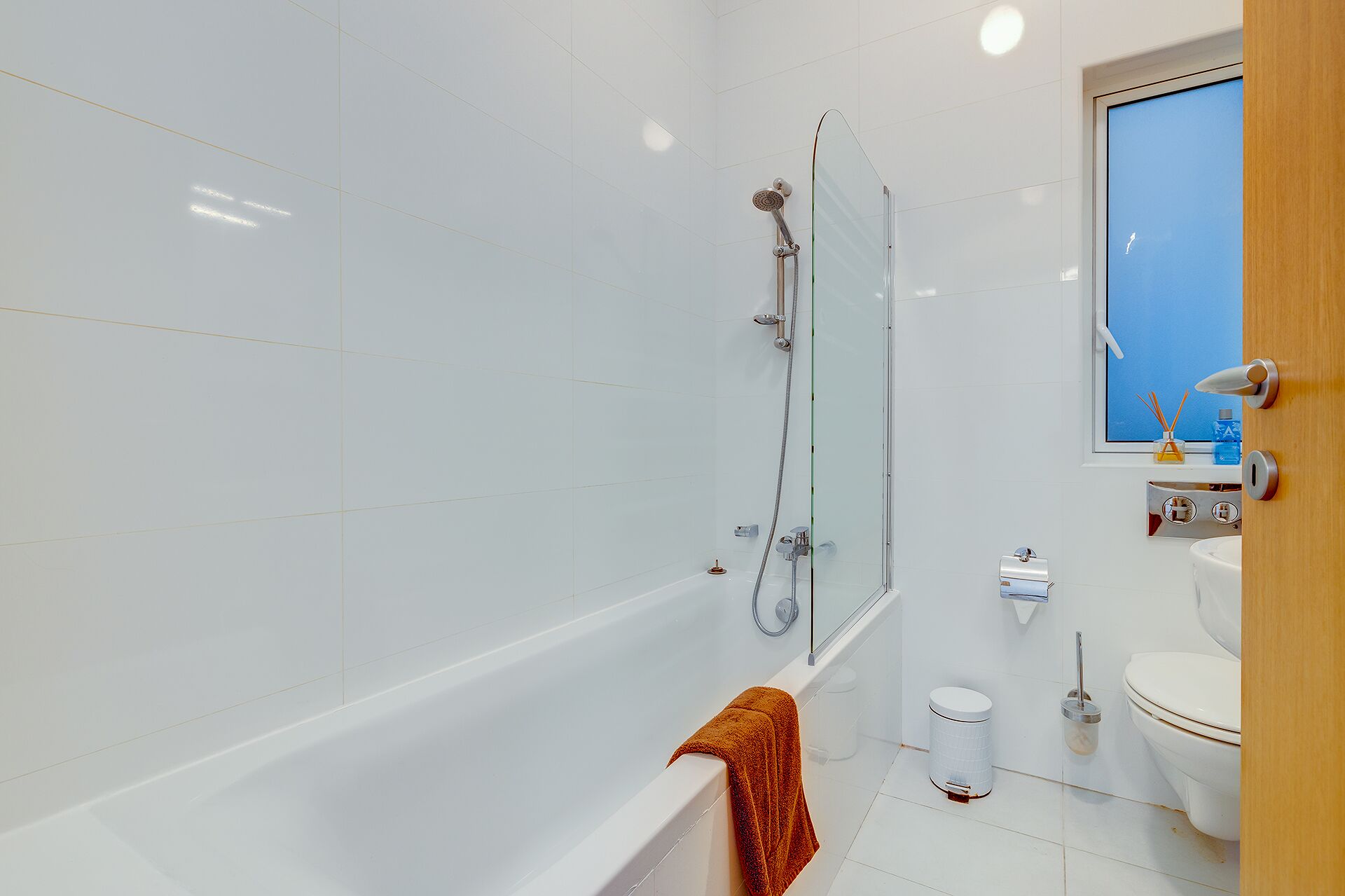 Une salle de bain moderne équipée d’une baignoire, d’une douche, de toilettes et d’une fenêtre.