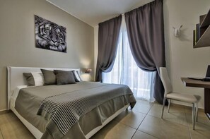 A bedroom with a large bed, a desk, and a chair. There is a window with curtains and a painting of a tiger on the wall. - Luxury Apartment With Pool and Terrace, Top Location (Sliema)