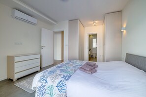 Quarto com cama, mesa de cabeceira, guarda-roupa e aparelho de ar condicionado.