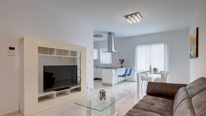 A modern living room with a flat-screen TV, a glass coffee table, and a brown sofa. - Spacious Apartment Steps to the Promenade (Gzira)