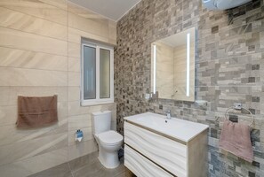 A bathroom with a toilet, sink, and mirror. - Spacious Apartment Steps to the Promenade (Gzira)