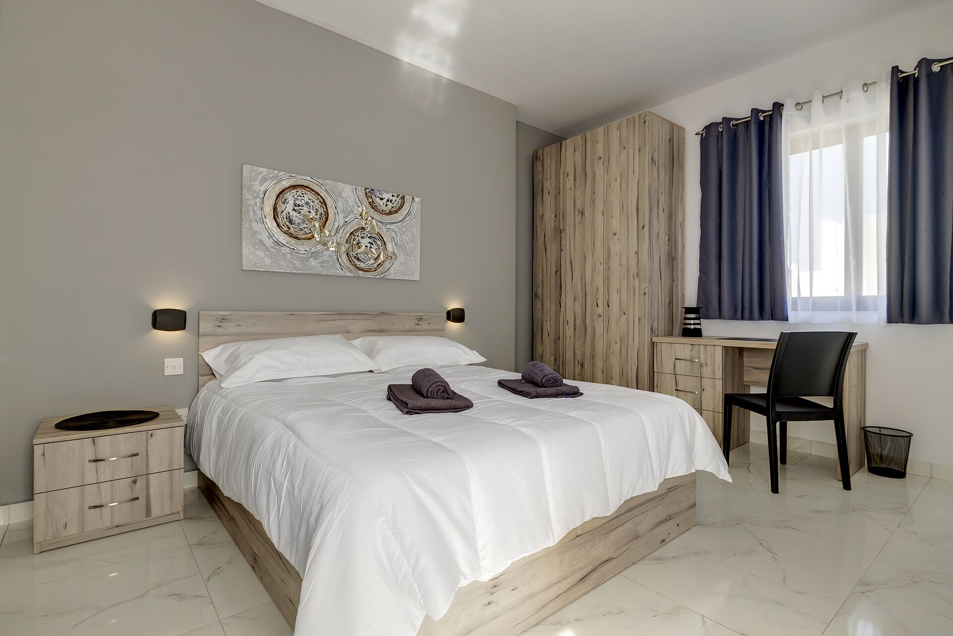 Un dormitorio moderno con una cama grande, un armario de madera, un escritorio y una silla.