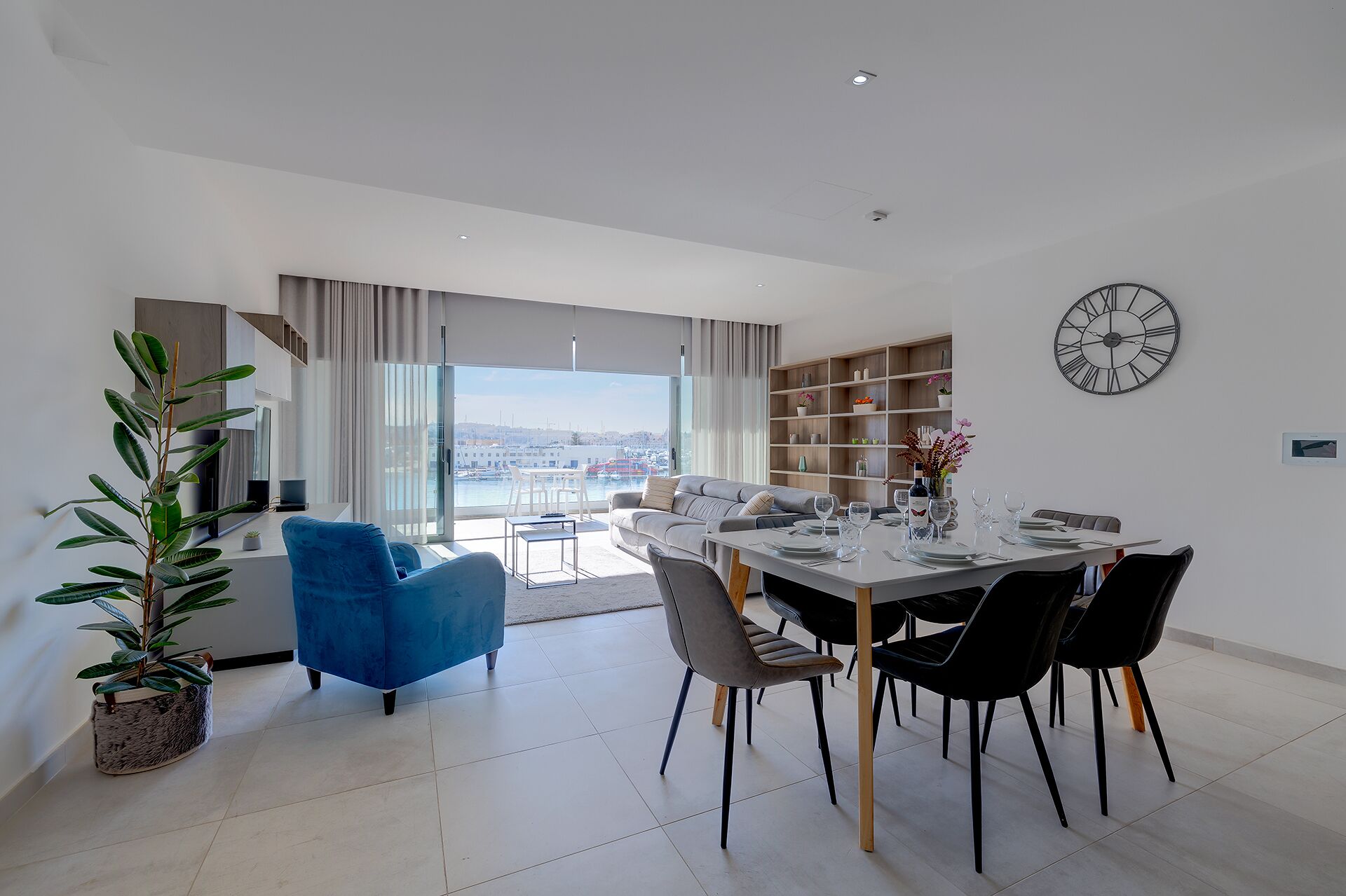 A modern living room with a dining area, large windows, and a view of the city.