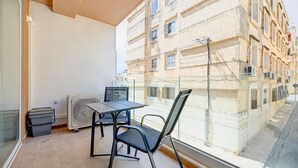 A balcony with a table and chairs, a radiator, and a trash bin. - Chic 2BR Apartment, Ideal Location (Ta' Xbiex)