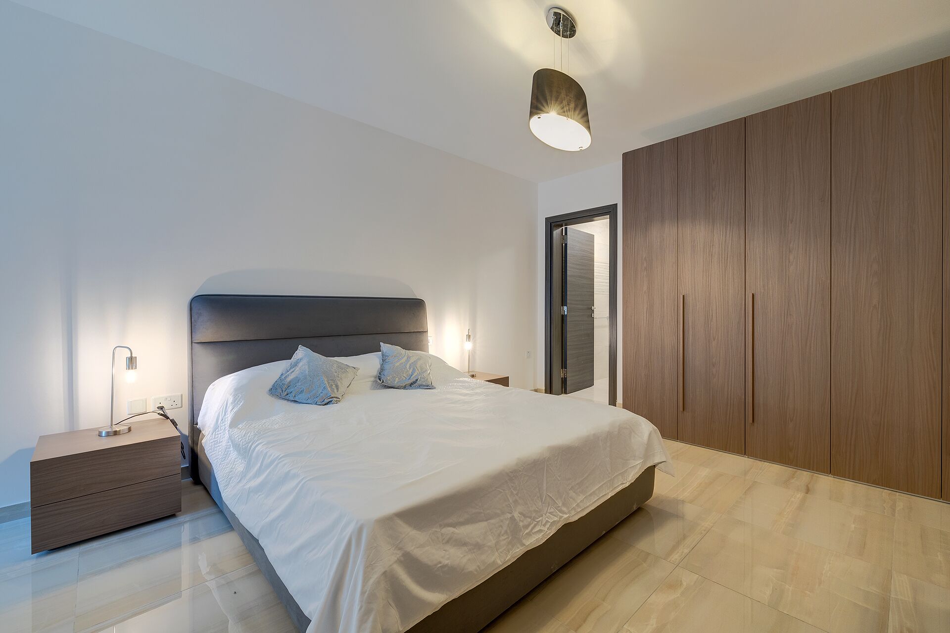 Un dormitorio moderno con una cama grande, lámparas de noche, un armario y una luz de techo.