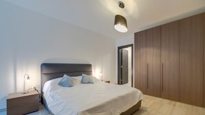 A modern bedroom with a large bed, bedside lamps, a wardrobe, and a ceiling light. - Chic 2BR Apartment, Ideal Location (Ta' Xbiex)