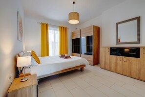 Ein modernes Hotelzimmer mit Bett, Nachttisch, Lampe, Kleiderschrank und einem großen Spiegel.