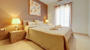 Une chambre à coucher comprenant un lit, des lampes de chevet, une table de chevet, un climatiseur fixé au mur et une fenêtre avec des rideaux.