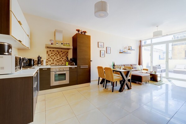 A modern kitchen with a dining area, featuring a large window and a view of the city. - Cosy 1BR Penthouse Close to the Promenade (Sliema)