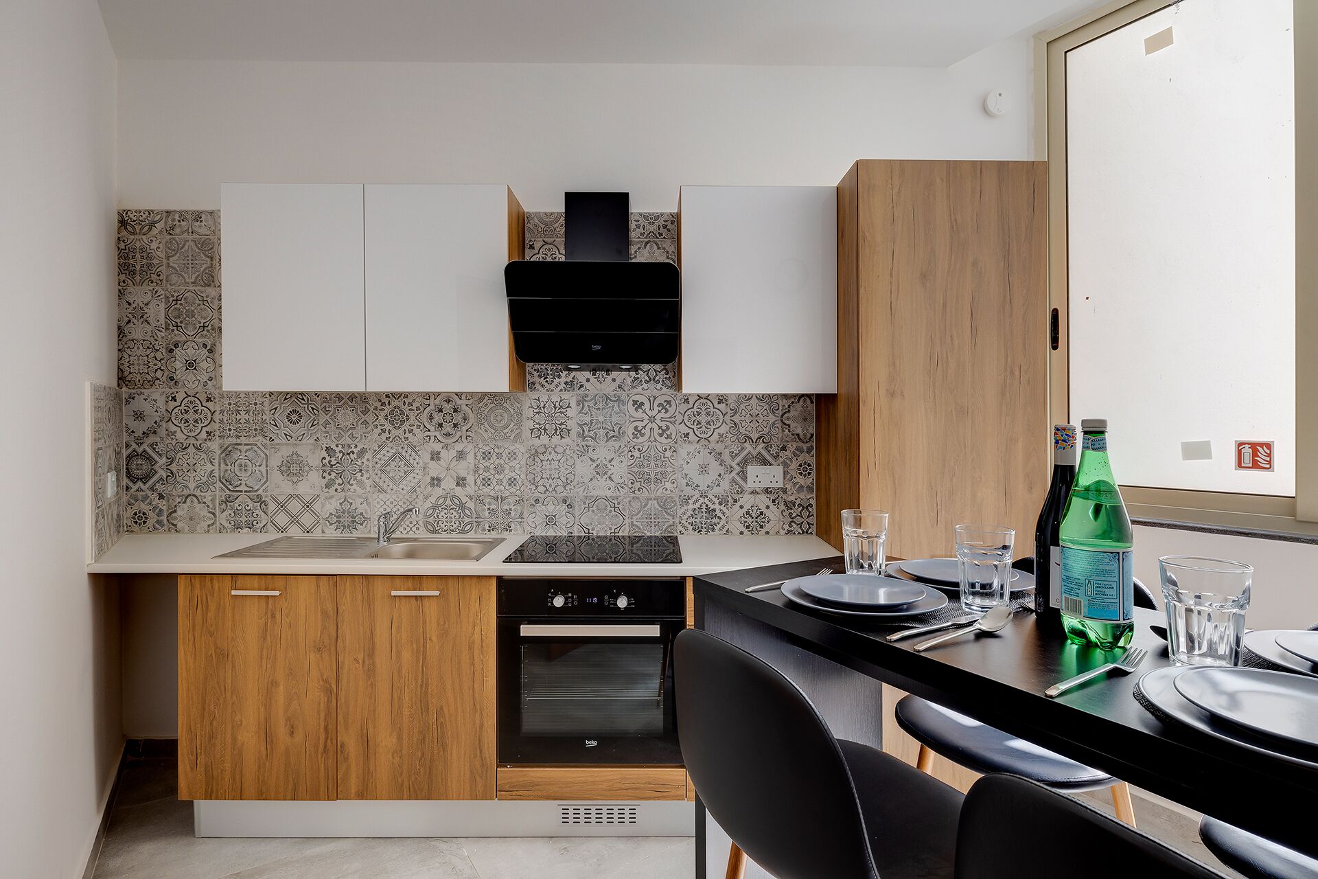Eine moderne Küche mit Holzschränken, einem schwarzen Herd und einer gefliesten Spritzschutzwand.
