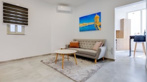 Uma sala de estar moderna com um sofá, uma mesa redonda pequena e um quadro na parede.