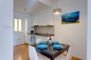 A modern kitchen with white cabinets, a black countertop, and a dining area with a table set for four.