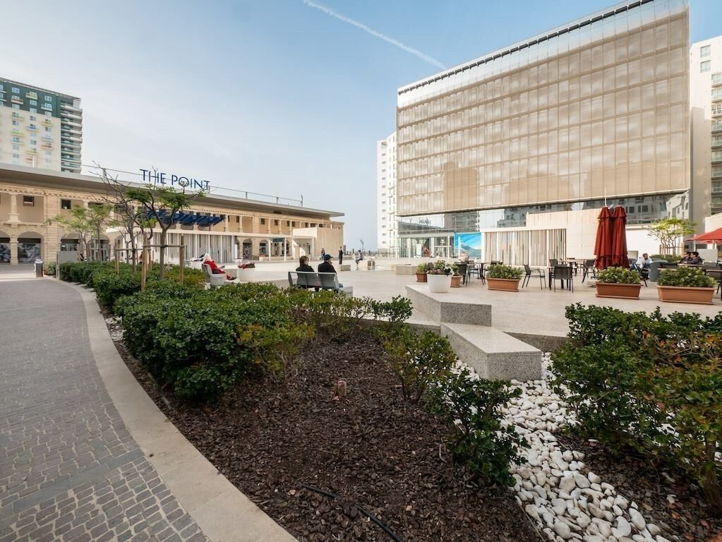 Ein Hotel mit moderner Fassade, einer Sitzgelegenheit im Freien und einem angelegten Garten.