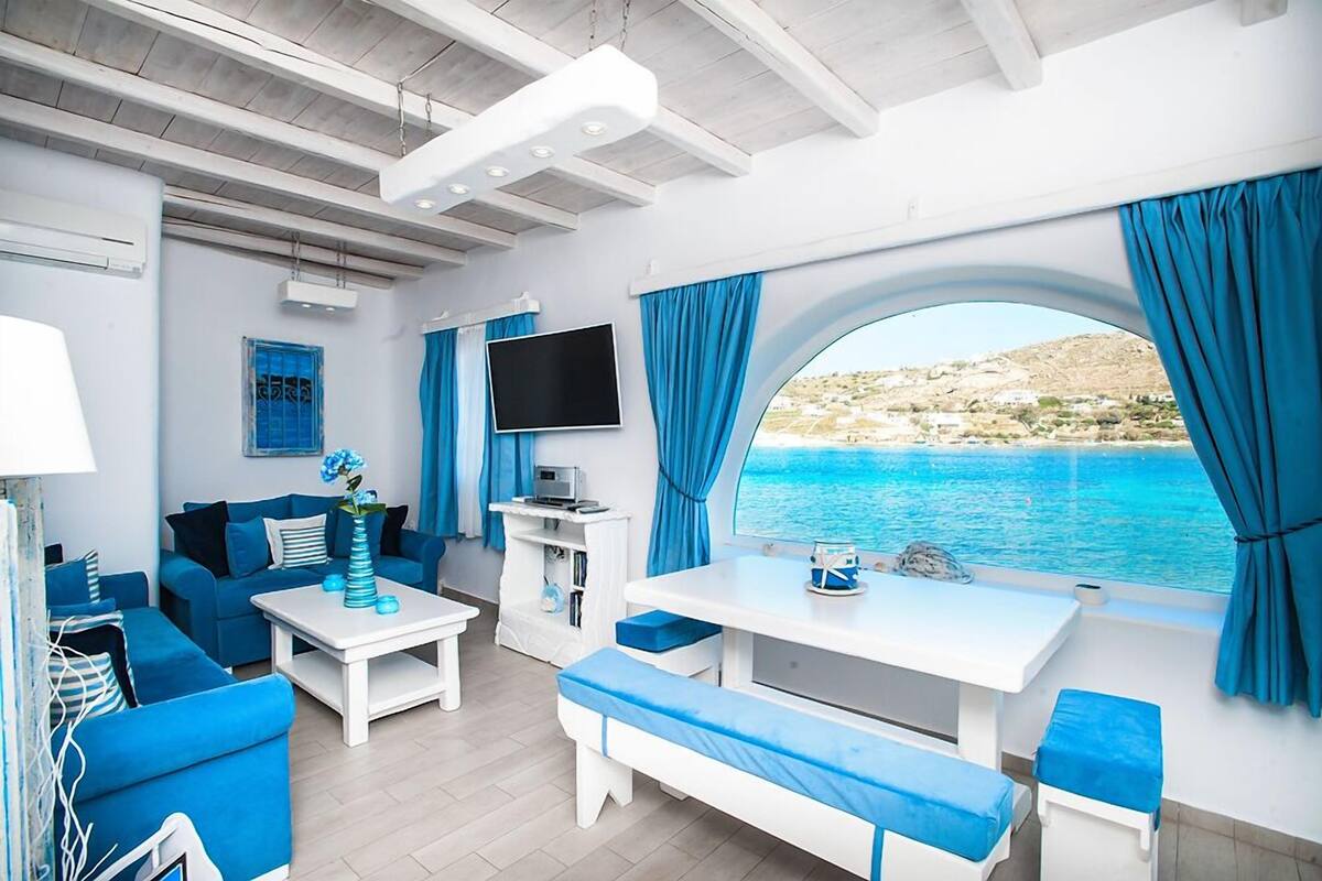 A modern living area with a sofa, coffee table, and TV, overlooking a scenic coastal view.