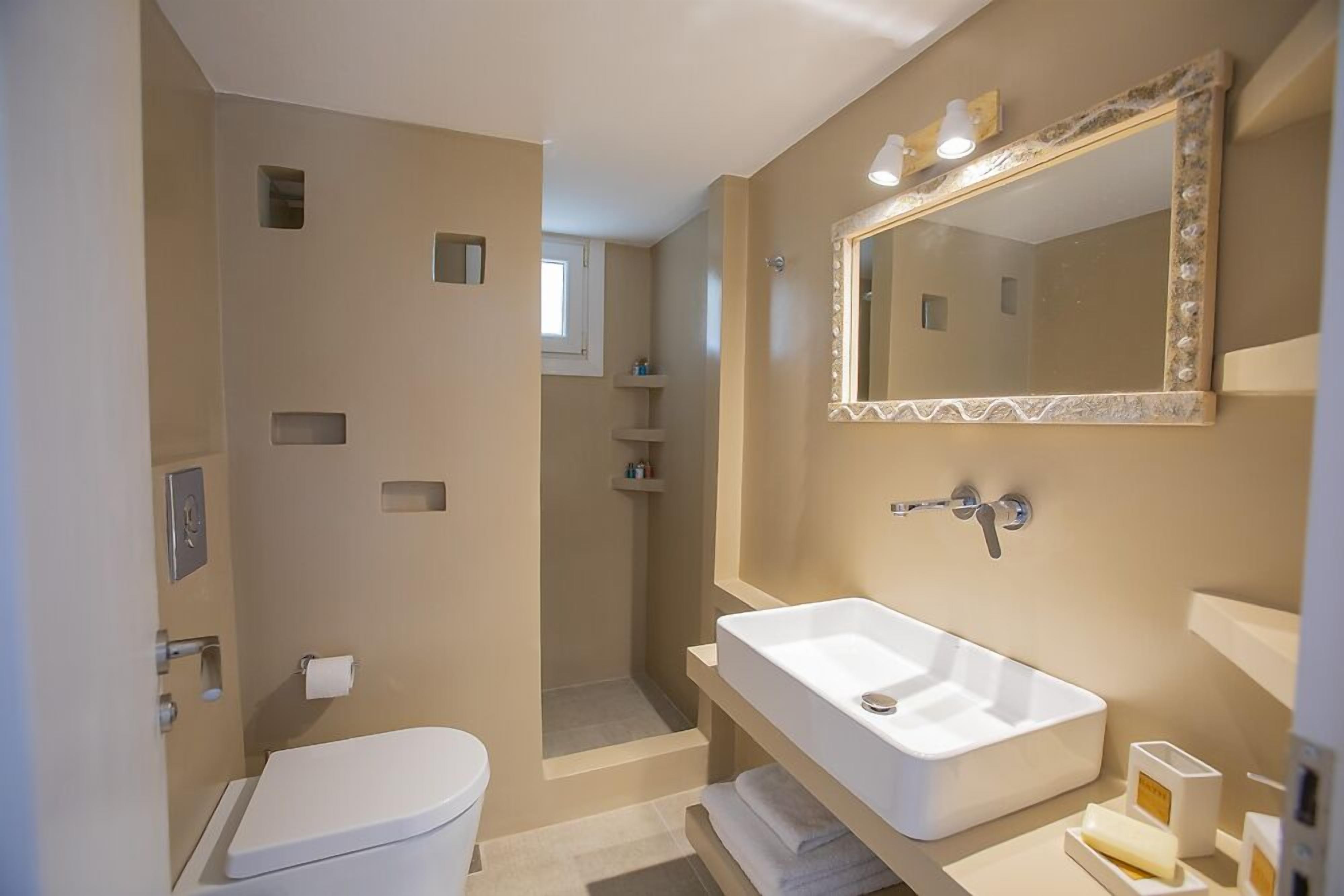 A modern bathroom with a white sink, a large mirror, and a shower area.