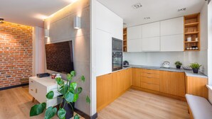 Een moderne keuken met houten kasten, een accentmuur van baksteen en een inbouwoven.