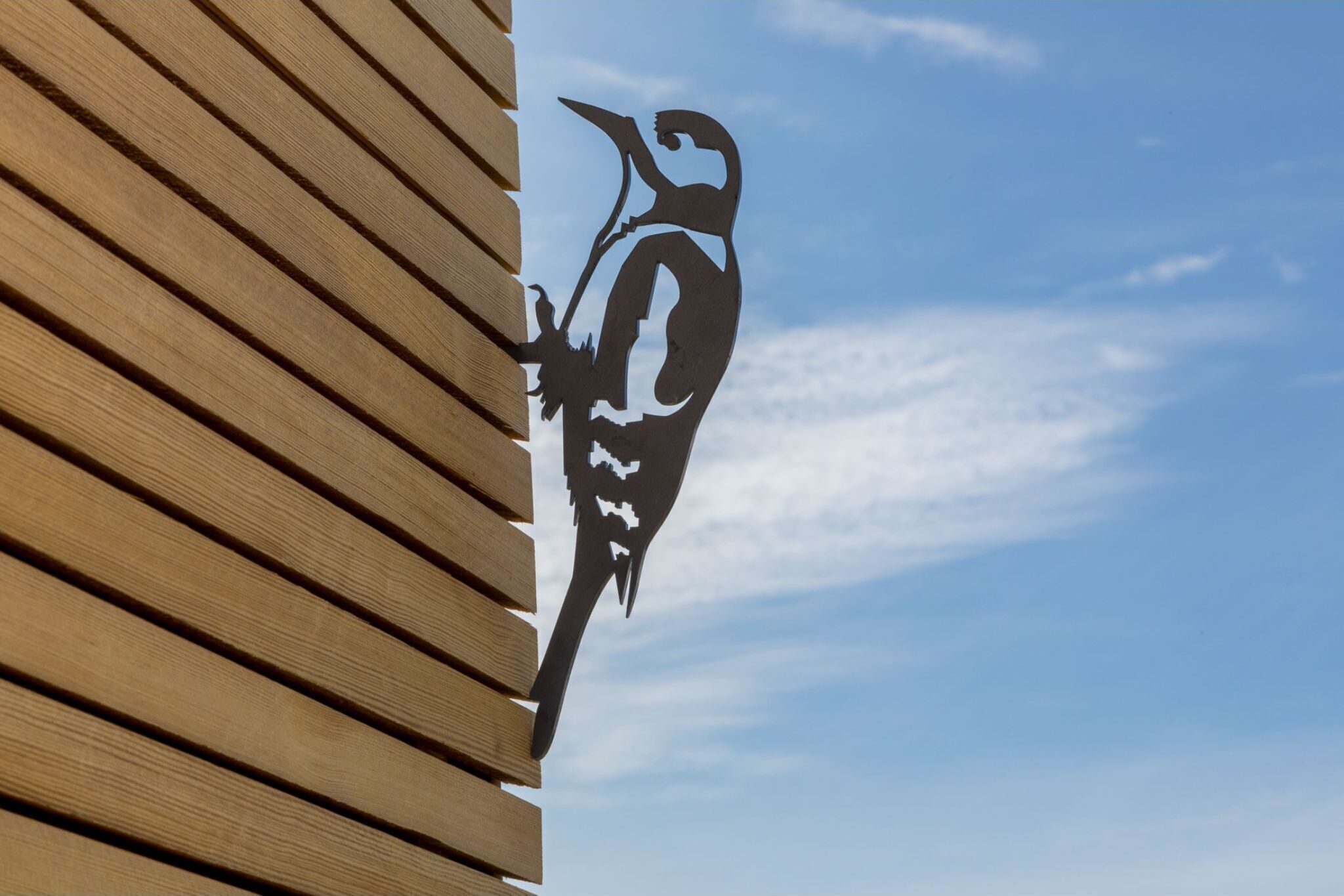 A wooden slat wall with a black silhouette of a bird.