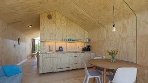 Een moderne keuken met houten kastjes, een eettafel met stoelen en een hangende lamp.