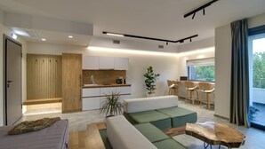 A modern living room with a sofa, a wooden coffee table, and a dining area with chairs. - Selin Luxury Residences (Ioannina)