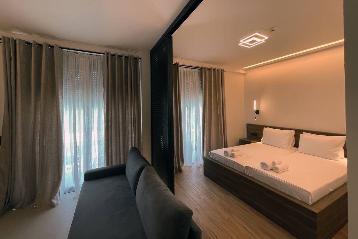 Una habitación de hotel con una cama, un sofá y cortinas.