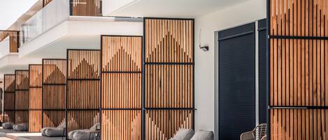 A modern hotel with a pool area, wooden panel dividers, and outdoor seating.