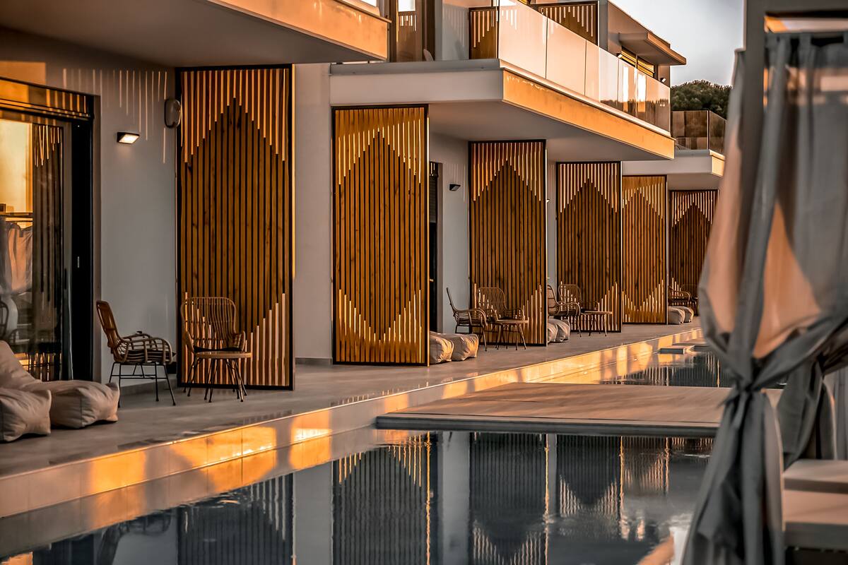 Un hotel moderno con zona de piscina, que presenta un diseño elegante con paneles verticales de madera y asientos cómodos.