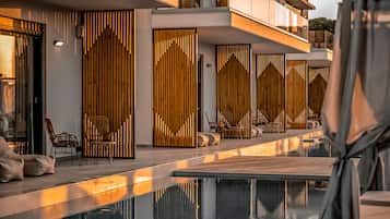A modern hotel with a pool area, featuring a sleek design with vertical wooden panels and comfortable seating.