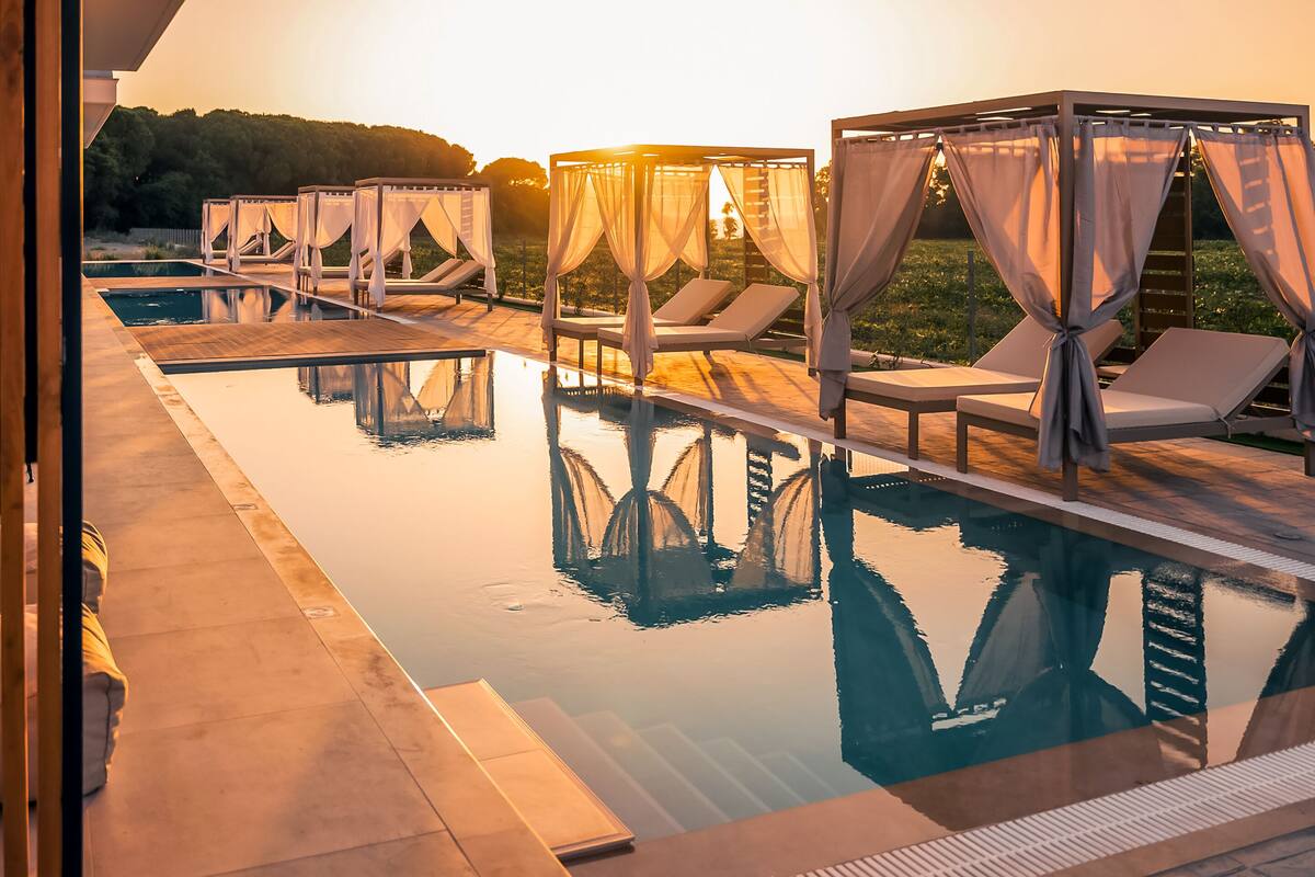 Zona junto a la piscina con tumbonas y áreas de descanso con toldos.