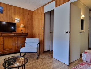 A room with a television, a chair, a table, and a sliding door.