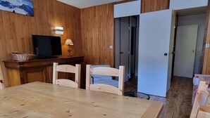 Una stanza con pannelli in legno, un tavolo da pranzo, sedie, un televisore e una lampada.