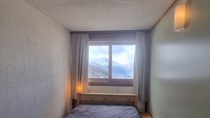 Una stanza piccola e stretta con un letto singolo, una finestra con tende e una luce notturna.