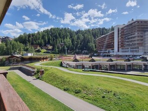 A hotel with a modern design, a parking area, and a view of a forested hill.