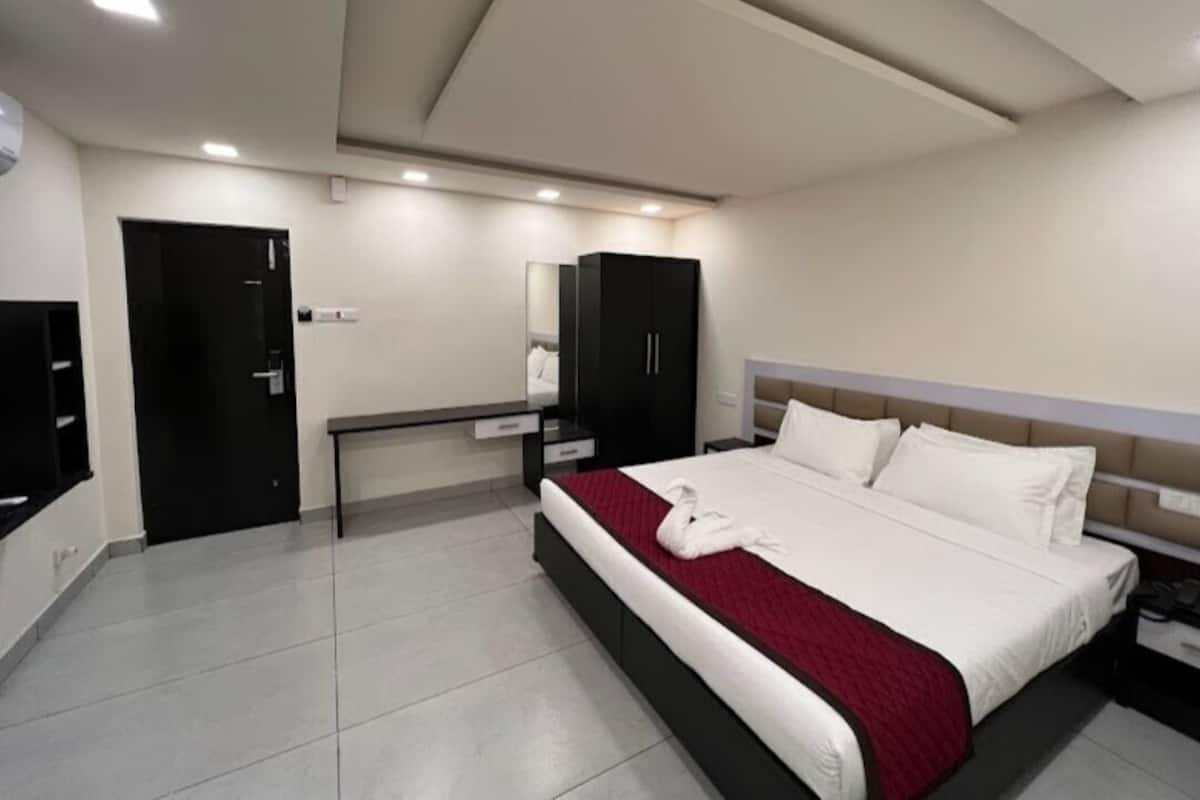 A hotel room with a bed, a desk, a wardrobe, and a mirror.