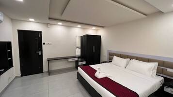 Una habitación de hotel moderna con una cama grande, una mesita de noche, un armario y un televisor de pantalla plana.