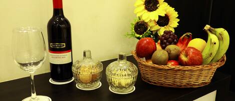 A wine bottle, a glass, and a fruit basket on a table.