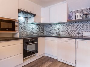 Een moderne keuken met een magnetron, oven en vaatwasser.