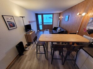A compact living space with a wooden dining table, a sofa, and a television.
