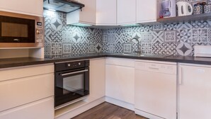 Eine moderne Küche mit weißen Schränken, einer Mikrowelle, einem Backofen und einem Geschirrspüler.