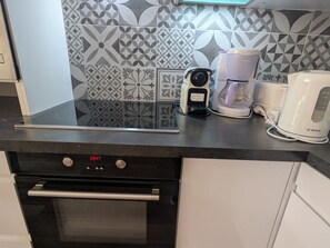 A kitchen with a black oven, a coffee maker, and a kettle on the counter. - Duplex Apartment 2 Rooms · Ski-in/Ski-out · Terrace (Plagne Villages)
