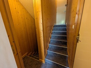 A wooden staircase with carpeted steps leading to a room with a white door.
