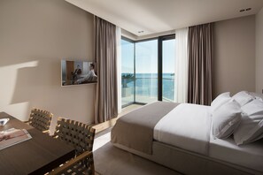 A hotel room with a bed, a dining table, chairs, a TV, and a balcony with a view of the sea. - Owner site/ Most Luxurious Villa in Dubrovnik, Seafront, Amazing View (Dubrovnik)