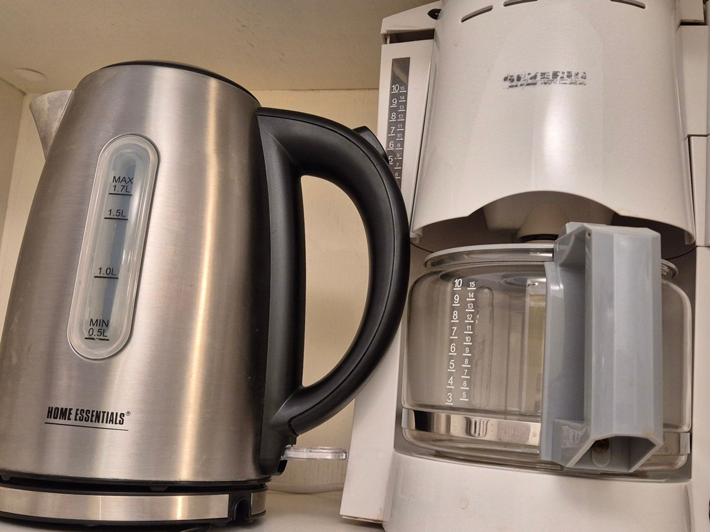Uma chaleira de aço inoxidável com graduações de medição e uma cafeteira com jarra de vidro.