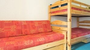 Una cama litera con una cama inferior y un sofá cama con funda roja estampada.