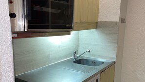Una cocina compacta con un lavamanos de acero inoxidable, un microondas y un lavavajillas.