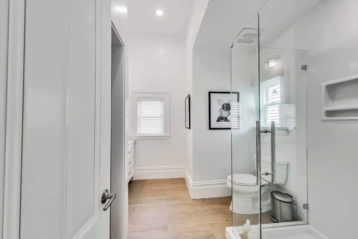 A modern bathroom with a glass shower enclosure, a white toilet, and a framed picture on the wall.