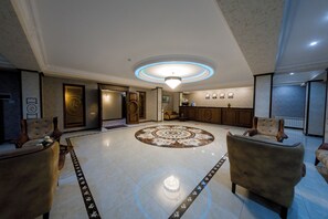 A spacious lobby with a central chandelier, a reception desk, and seating areas. - Royal Sapphire Hotel (Baku)